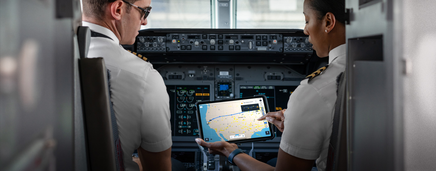 Dwoje pilotów w kokpicie patrzących na iPada z otwartą mapą.